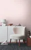 A cozy interior scene featuring a fluffy white chair and a white cabinet with decorative items. Produktbild-Vorschau