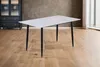 A rectangular dining table with a white marble-like top and black legs is shown in a room with wooden floors and a dark cabinet in the background. Produktbild-Vorschau