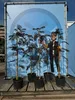 Several potted trees are displayed in front of a large blue banner featuring a cartoon character and a height measurement. Produktbild-Vorschau