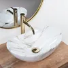 A close-up shot of a marble-patterned vessel sink with a gold faucet. Anteprima dell’immagine prodotto