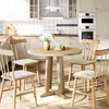 A round wooden dining table with four chairs in a bright, modern kitchen. Produktbild-Vorschau