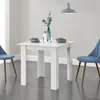 A white square dining table with two blue chairs and place settings for four people. Voir les images du produit