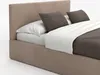 A close-up view of a bed with a beige upholstered headboard and frame, white sheets, and brown pillows. Náhled obrázku produktu