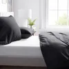 A close-up view of a bed with black bedding. Produktbild-Vorschau