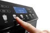 A close-up shot of a finger pressing a button on a coffee machine's control panel. Produktbild-Vorschau