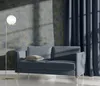 A modern living room scene with a blue sofa, a floor lamp, and textured wallpaper. Produktbild-Vorschau
