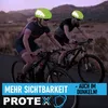 Two cyclists wearing helmets on a road at dusk. Produktbild-Vorschau