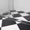 A close-up view of a shower door track and a black and white checkered floor. Náhled obrázku produktu