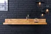 A wooden shelf mounted on a black brick wall, decorated with candles and a glass dome lamp. Produktbild-Vorschau