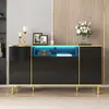 A black sideboard with gold trim and LED lighting, decorated with framed pictures, candle holders, and a vase of flowers. Produktbild-Vorschau