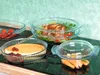 Several glass casserole dishes filled with food are arranged on a stovetop. Produktbild-Vorschau