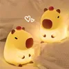 Two illuminated capybara-shaped night lights on a bed. Podgląd zdjęcia produktu