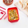 A red food container filled with soup, next to bread slices on a wooden board. Anteprima dell’immagine prodotto