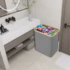 A laundry basket filled with clothes is placed next to a bathroom vanity. Voir les images du produit