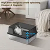 A cat is sitting in a litter box in a room with furniture. Voir les images du produit