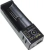 A close-up, angled view of a black and gray universal battery charger with a USB port. Náhled obrázku produktu