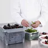 A chef is preparing mussels and garnishes for plating. Produktbild-Vorschau