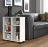 A white shelf unit with books, a clock, and a candle sits next to a dark leather sofa in a living room. Náhled obrázku produktu