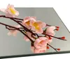 A branch of artificial pink flowers with yellow centers rests on a mirrored surface. Produktbild-Vorschau