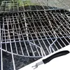 A close-up view of a grill grate with a grill tool in the foreground. Voir les images du produit