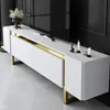 A white TV stand with gold accents is shown in a room with a black wall and a black television. Náhľad obrázku produktu