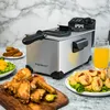 A deep fryer is shown on a countertop with fried food and a glass of orange juice. Produktbild-Vorschau