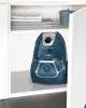 A blue and silver Rowenta vacuum cleaner is placed on a shelf inside a white cabinet. Náhľad obrázku produktu