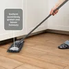 A person is using a mop to clean a wooden floor in a kitchen or utility room. Produktbild-Vorschau