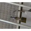 Close-up view of two metal heating elements with white residue, set against a perforated ceramic surface and metal bars. Produktbild-Vorschau