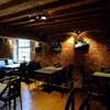 Interior of a restaurant or cafe with brick walls, wooden beams, and tables with chairs. Podgląd zdjęcia produktu