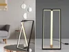 A split image showing a modern LED table lamp in two different settings. The left side shows the lamp in a living room setting on a coffee table, with a sofa and wall art in the background. The right side shows the lamp against a plain gray background. Náhľad obrázku produktu