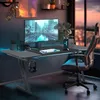 A modern gaming desk setup with a computer, keyboard, and chair in a room with city views at sunset. Produktbild-Vorschau