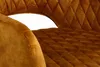 A close-up view of the quilted upholstery of a mustard yellow bar stool, showing stitching detail and a glimpse of a golden foot. Produktbild-Vorschau