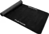 A black Playseat floor mat is shown rolled up on one end and unrolled on the other. Produktbild-Vorschau