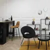 A modern living room or dining area with a bar stool, a chair, a small table, and shelving units. Voir les images du produit