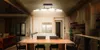 A modern kitchen and dining area with a large island and a dining table in the foreground, illuminated by a curved LED ceiling light. Produktbild-Vorschau