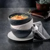 A stack of three textured bowls, one filled with soup, sits on a dark textured surface next to a folded napkin and spoon. Podgląd zdjęcia produktu