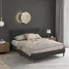 A bedroom scene with a bed, nightstand, and lamp. Produktbild-Vorschau