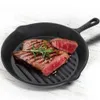 A cast iron grill pan with two steaks and a sprig of rosemary on a white wooden surface. Anteprima dell’immagine prodotto