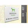 A sign for a veterinary practice mounted on a textured wall next to a dark gray door. Anteprima dell’immagine prodotto