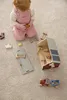 A child playing with wooden toys on a carpeted floor. Produktbild-Vorschau