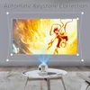 A mini projector is projecting an image onto a wall, demonstrating its keystone correction feature. The projector is placed on a coffee table. Produktbild-Vorschau