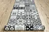 A runner rug with a patchwork tile design is laid out on a wooden floor. The rug is partially rolled up at the bottom. Produktbild-Vorschau