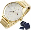 A close-up shot of a gold Tommy Hilfiger watch with a white face, displayed with its packaging. Produktbild-Vorschau