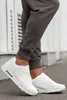 A person wearing white sneakers and gray sweatpants. Produktbild-Vorschau