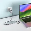 A Satechi USB-C multiport adapter is connected to a laptop, which is charging via a wall adapter and cable. Produktbild-Vorschau