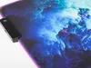 A close-up view of a gaming mousepad with an abstract, cloudy design in shades of blue, purple, and pink. A black control module is attached to the left edge of the mousepad. Náhľad obrázku produktu