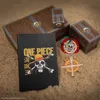 A collection of One Piece themed merchandise arranged on a sandy surface. Produktbild-Vorschau