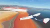 An Icon A5 aircraft flying over colorful salt flats near a body of water. Produktbild-Vorschau