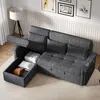A dark gray sectional sofa with its storage compartment open, revealing pillows and a blanket inside. The sofa is in a living room setting with a floor lamp and artwork on the wall. Produktbild-Vorschau